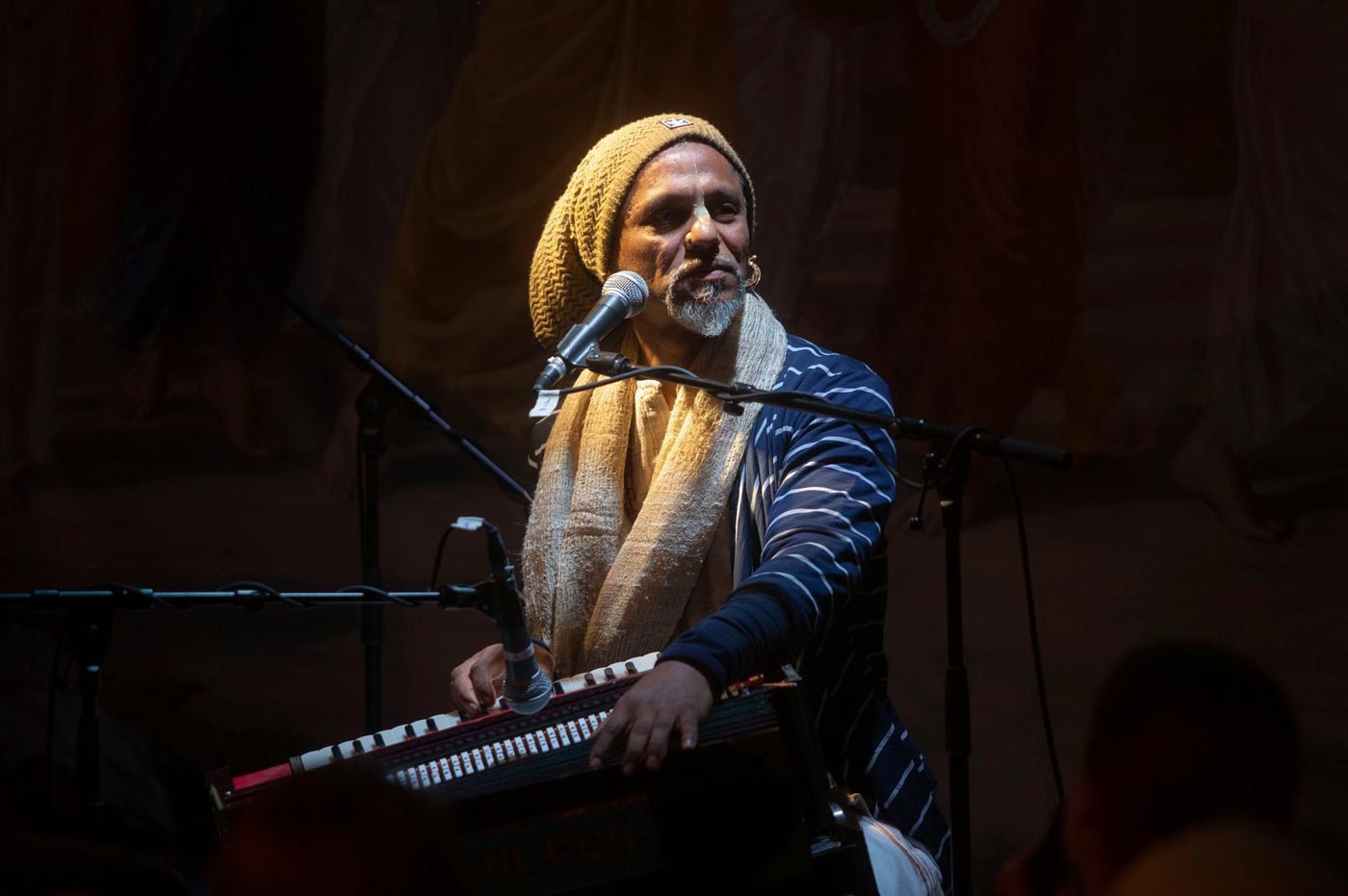 Madhava Das singing kirtan at the harmonium on stage